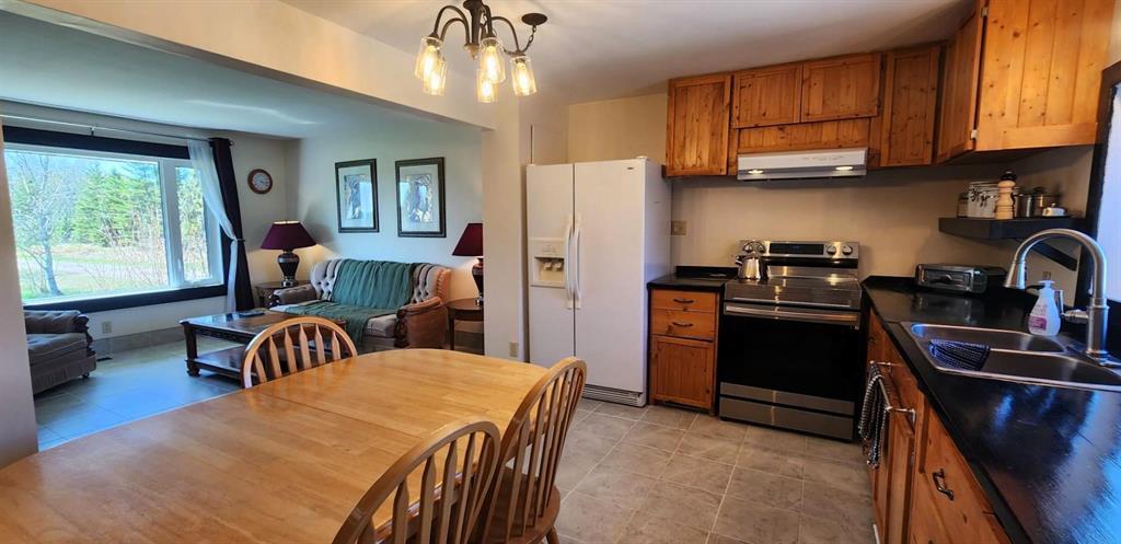 Open kitchen and living area at 117031 17E Road with custom cabinetry and a skylight