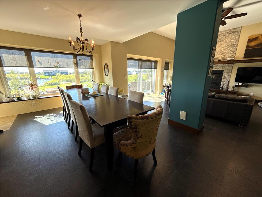 20053 Minerva Road &middot; the dining table under a chandelier against a wall of windows to the water