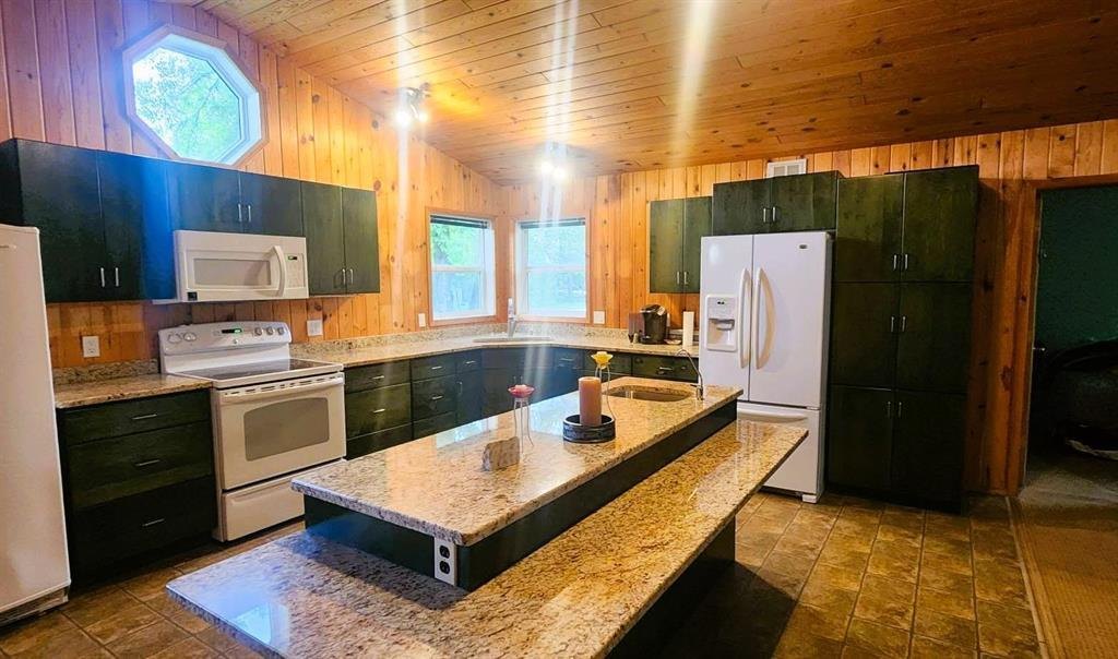 325 Epsilon Avenue, Winnipeg Beach &middot; open-concept kitchen with a granite island, dark cabinets and pine walls