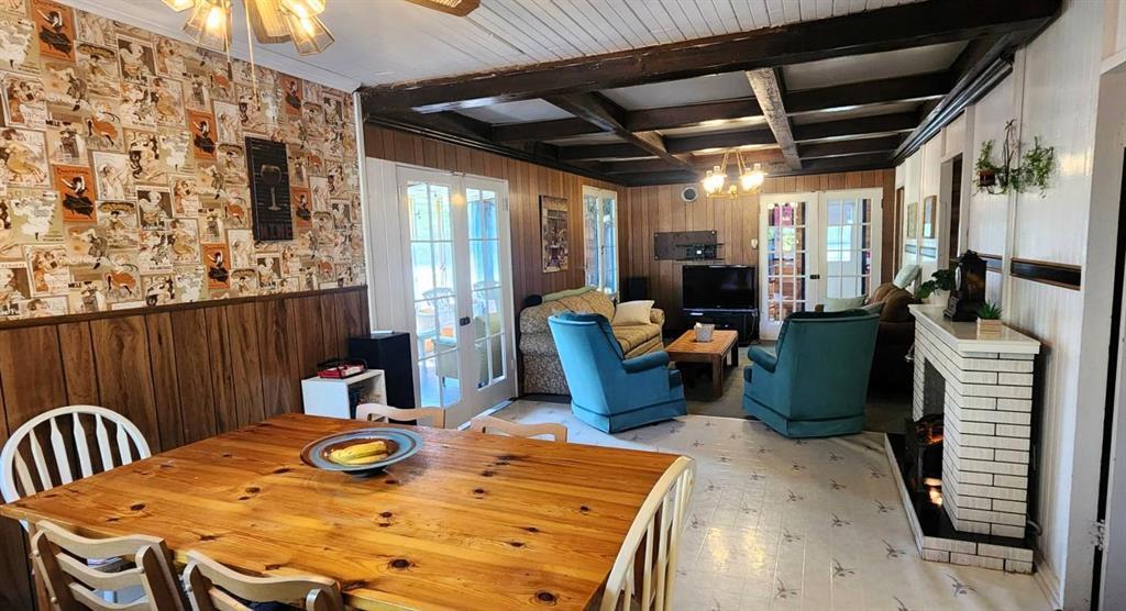 The living and dining room at 405 Silverdale Avenue, with a wood-beam ceiling and brick fireplace