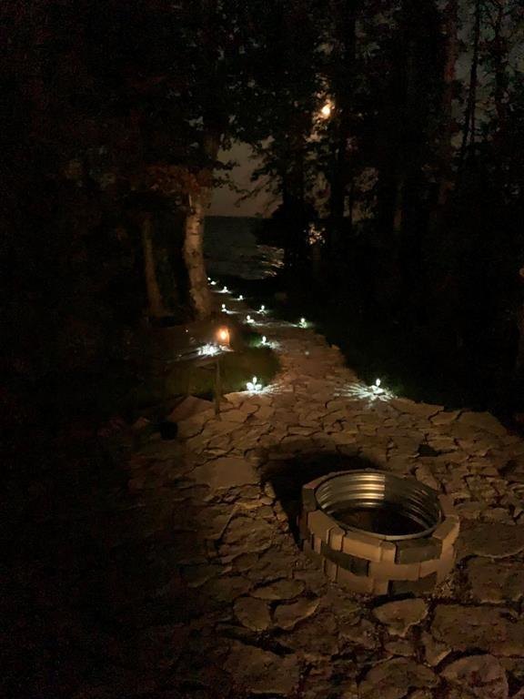 41 Little Deer Road &middot; the firepit lit at night with path lighting through the trees