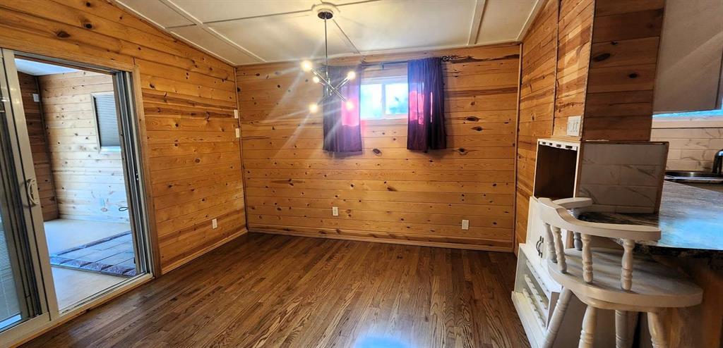 418 Oak Avenue, Winnipeg Beach · dining room with wood flooring, opening to the sunroom and the kitchen bar