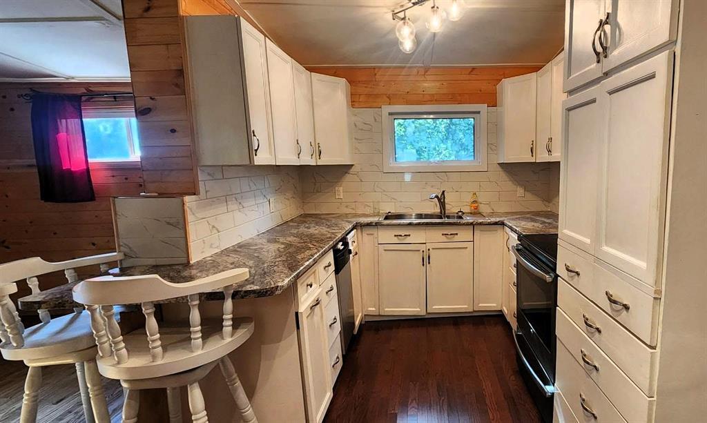 418 Oak Avenue, Winnipeg Beach · kitchen with white cabinetry, tile backsplash and a breakfast bar