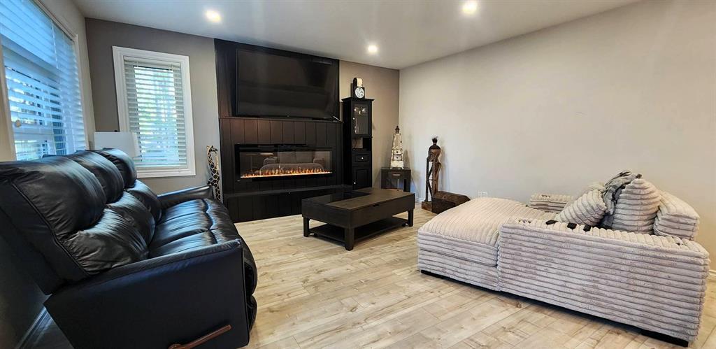 Living room at 529 Ash Avenue with electric fireplace, mounted TV, and sectional