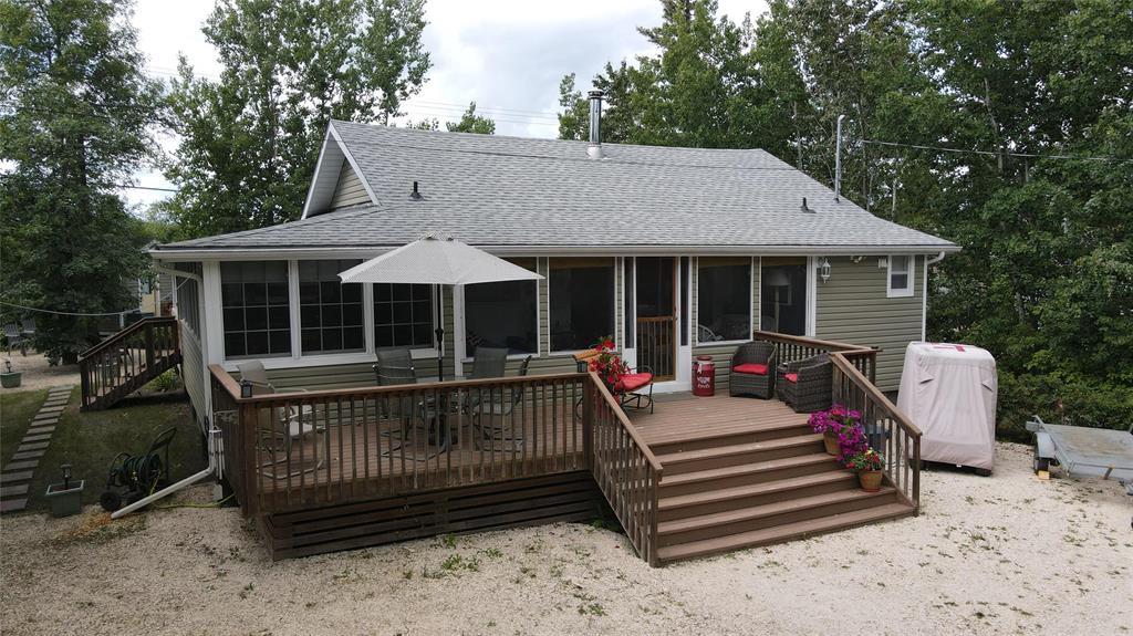 560 Prospect Street, Winnipeg Beach · the cottage from the yard with its deck and patio umbrella