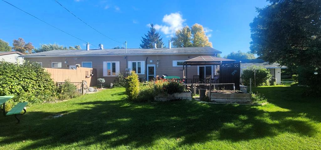 82 Willow Drive, Aspen Park &middot; the back of the home with the deck and gardens across the lawn