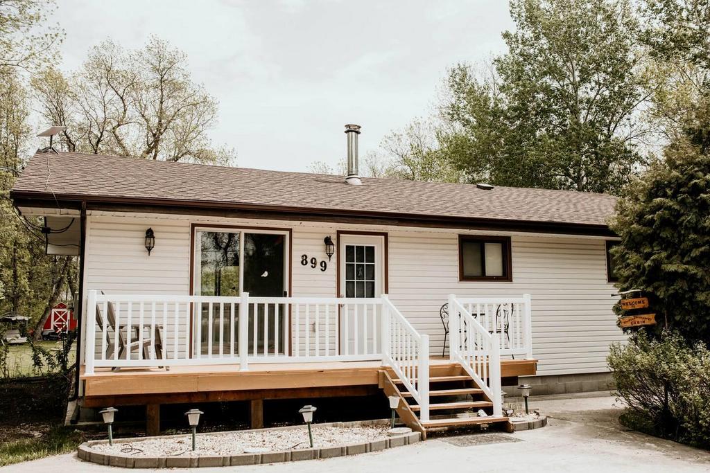 899 PTH 9 Highway, Winnipeg Beach &middot; the front of the bungalow with its white railed deck and paved driveway
